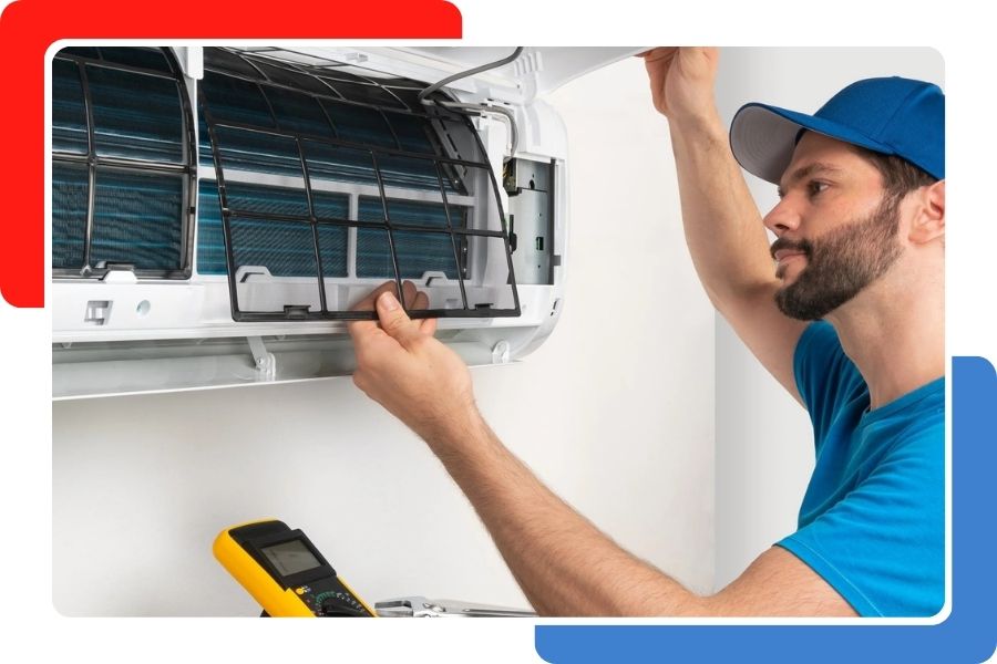 A technician in a blue shirt and cap removing or installing a mesh filter into a wall-mounted air conditioning unit.