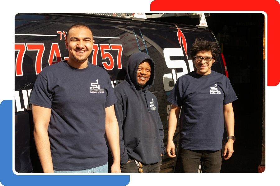 Three smiling male technicians in navy blue company shirts and a hoodie standing in front of a dark service van.