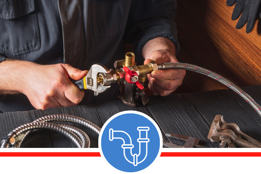 A close-up of a person's hands using an adjustable wrench to connect a flexible metal hose to a brass plumbing fixture.