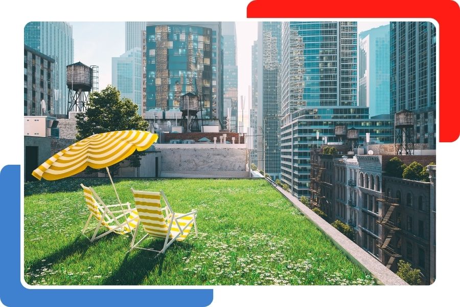 A lush green rooftop garden with two yellow-striped lounge chairs and an umbrella, surrounded by city skyscrapers.